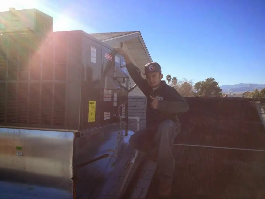 HVAC technician performing AC Tune-Up on a rooftop unit in Raymond